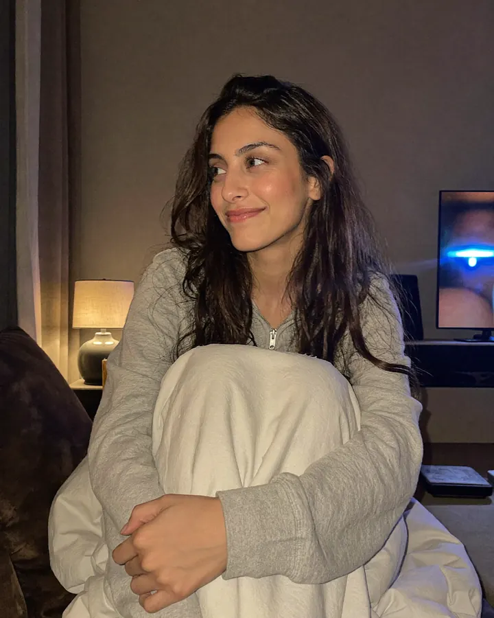 Aisha on the couch at night under a blanket, smiling at the TV